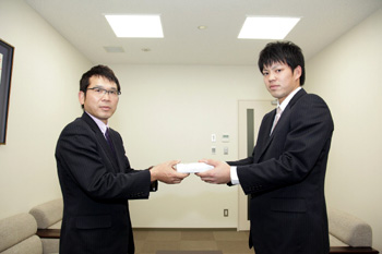 沼沢専務より記念品を受け取る藤井宏政選手。